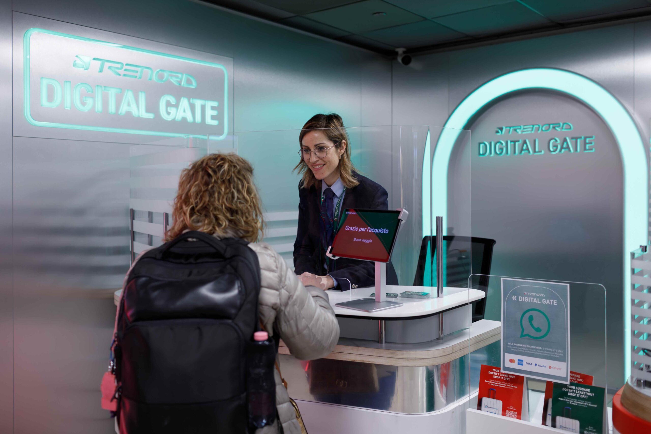 Sportello “Digital Gate” di Trenord a Milano Centrale con un’operatrice che assiste una cliente in un ambiente moderno e digitale.